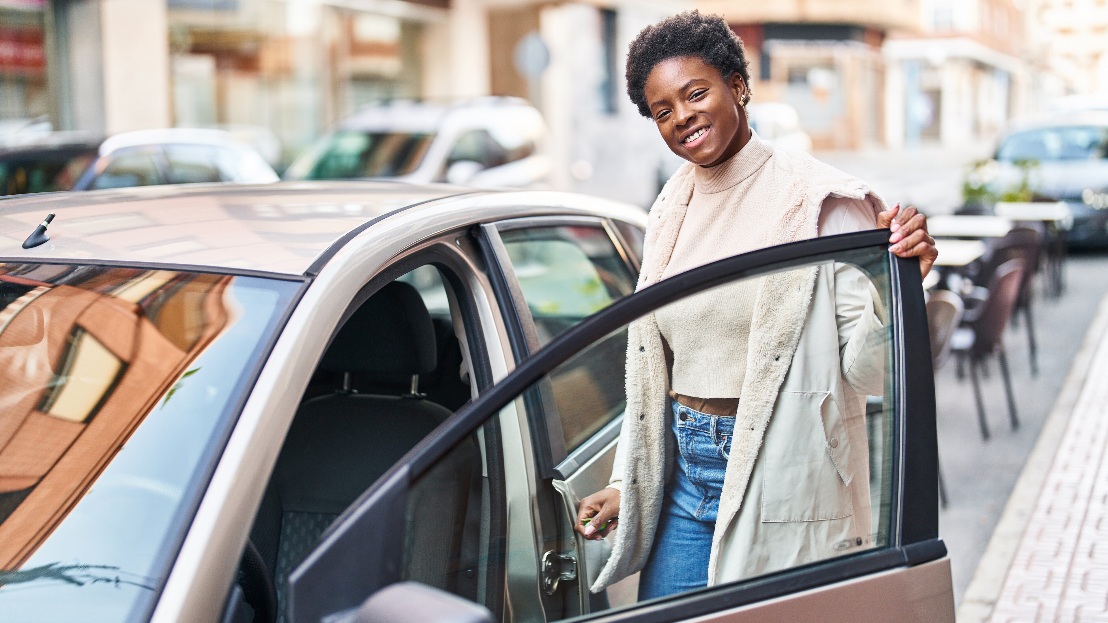 Jeune femme ouvrant la porte d'une voiture